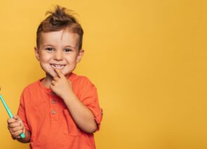 ילד מחזיק מברשת שיניים ומצביע על שן