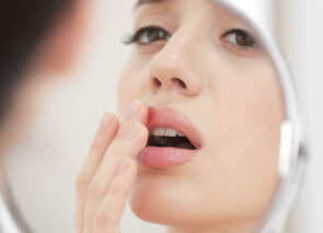 אישה מסתכלת במראה ונוגעת באזור הפה